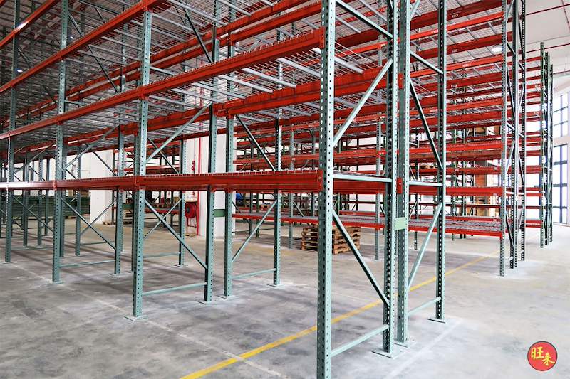 Pallet racking runs on either side of an aisle, green uprights and orange beams throughout - V3000 Racking - V3-3 | Wong Lye Racking, Singapore Racking Manufacturer