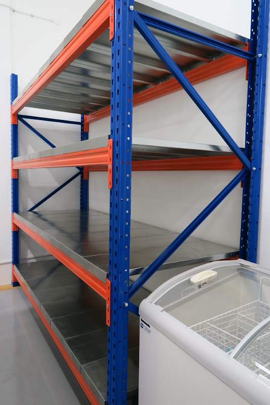 Long-span racking bay with blue uprights, orange beams and steel decking beside a chest freezer - Boltless Racking - B8 | Wong Lye Racking, Singapore Racking Manufacturer