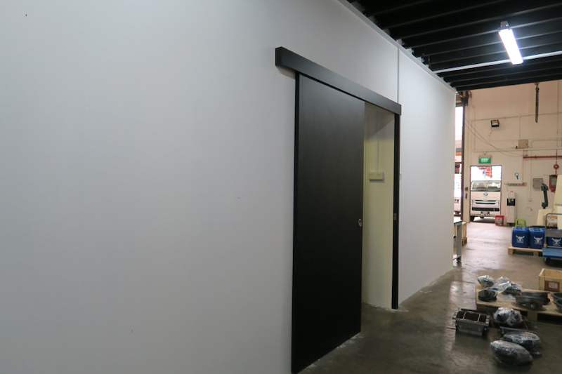 Black sliding door in a partition wall under the mezzanine, store floor beyond - V5000 Racking - V5-8 | Wong Lye Racking, Singapore Racking Manufacturer