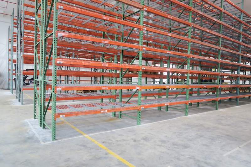 Long run of pallet racking with wire mesh decking on green uprights and orange beams, bays empty - V3000 Racking - V3-3 | Wong Lye Racking, Singapore Racking Manufacturer