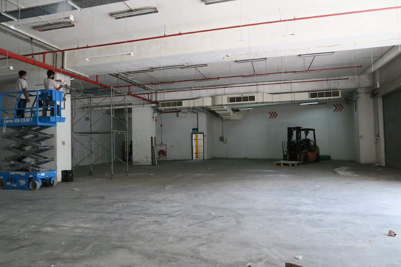 Before: bare warehouse unit with a scissor lift and forklift, before the epoxy floor and shelving - Boltless Racking - B7 | Wong Lye Racking, Singapore Racking Manufacturer