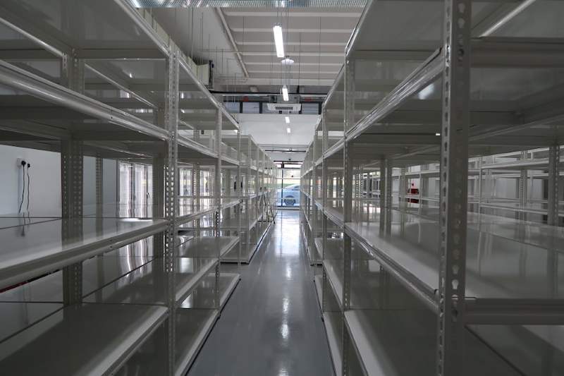 Long aisle between white boltless shelving with a glossy epoxy floor - Boltless Racking - B8 | Wong Lye Racking, Singapore Racking Manufacturer