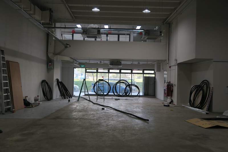 Before: empty unit with coils of cable on the concrete floor and glass frontage at the far end - Boltless Racking - B8 | Wong Lye Racking, Singapore Racking Manufacturer