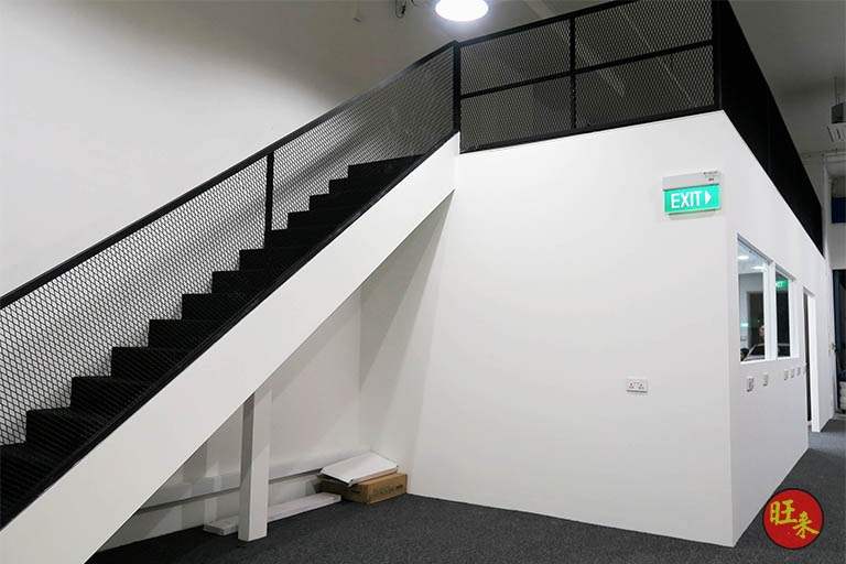 Steel staircase with mesh side panels rising to the mezzanine floor, black railing above the office - V5000 Racking - V5-13 | Wong Lye Racking, Singapore Racking Manufacturer