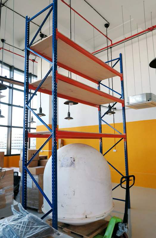 V3000 racking bay with orange beams and plywood decking against an orange wall, pallet on the floor - V3000 Racking - V3-4 | Wong Lye Racking, Singapore Racking Manufacturer