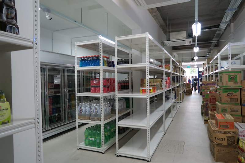 White boltless shelving stocked with bottled drinks beside glass-door chillers in the store - Boltless Racking - B6 | Wong Lye Racking, Singapore Racking Manufacturer