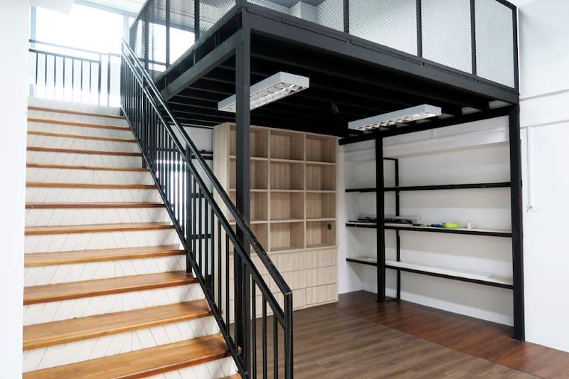 Timber staircase with black steel balustrade rising to the mezzanine deck, shelving and cabinets below - V5000 Racking - V5-16 | Wong Lye Racking, Singapore Racking Manufacturer